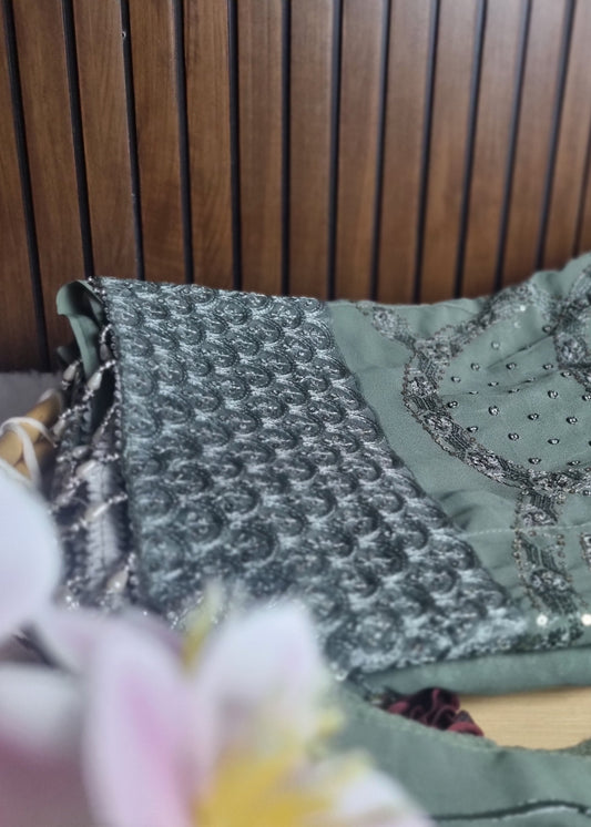 Green embroidered fabric with floral decorations on a wooden surface