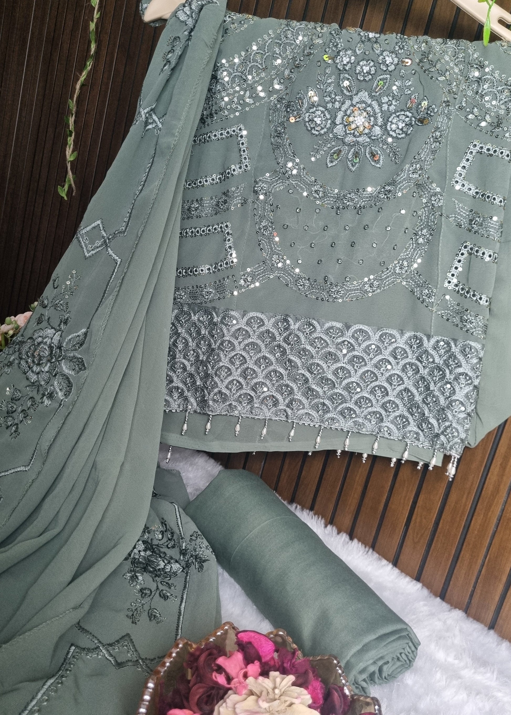 Green fabric with intricate silver embroidery on a wooden surface