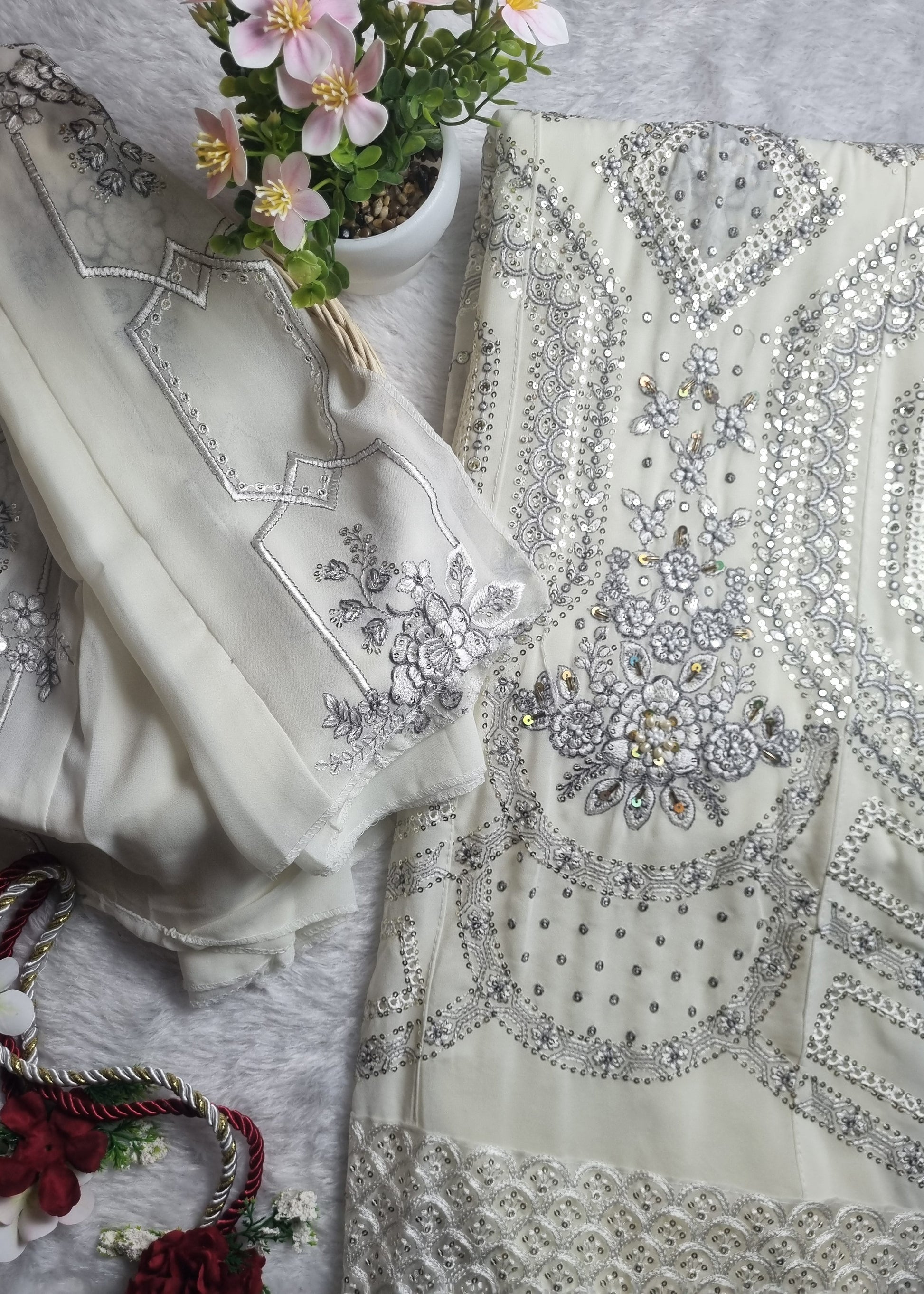 Decorative fabric with intricate silver embroidery on a textured surface with flowers.