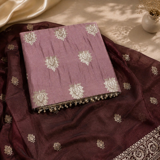 A folded lavender fabric piece with white floral embroidery rests on a draped dark maroon dupatta featuring metallic silver border patterns and small silver floral motifs, styled on a beige surface with soft shadows.