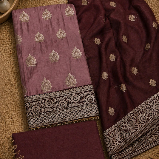 A folded traditional Indian salwar suit fabric set in dusty mauve and deep maroon, featuring silver floral embroidery and a detailed silver border, displayed on a textured beige jute mat.