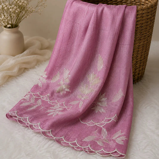 A dusty pink lightweight Dupatta with white floral embroidery and a scalloped edge, draped over a brown woven basket on a white faux fur surface.