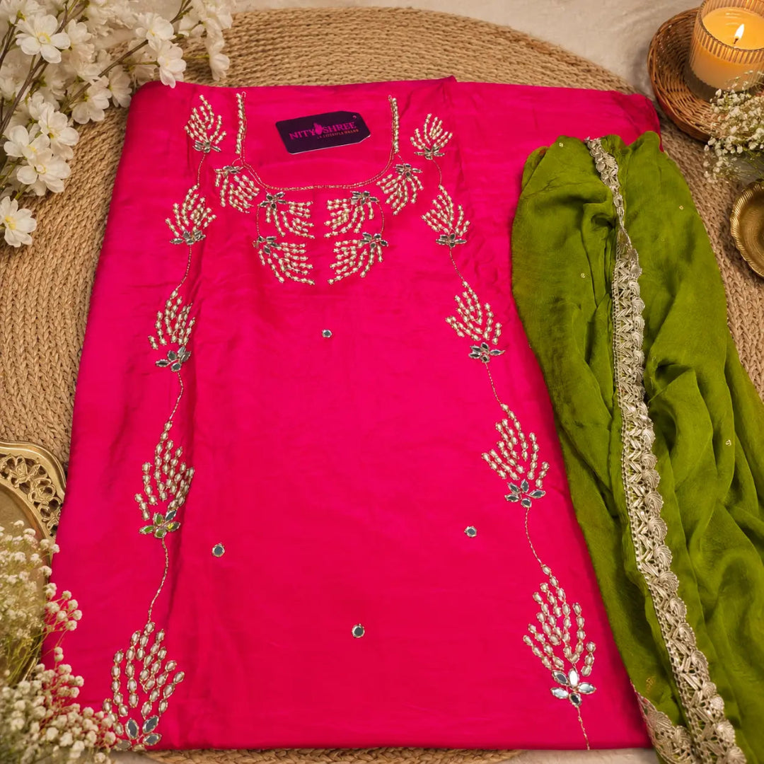 Fuchsia pink suit fabric featuring intricate embroidery, embellished neckline and sheer parrot green dupatta with lace border