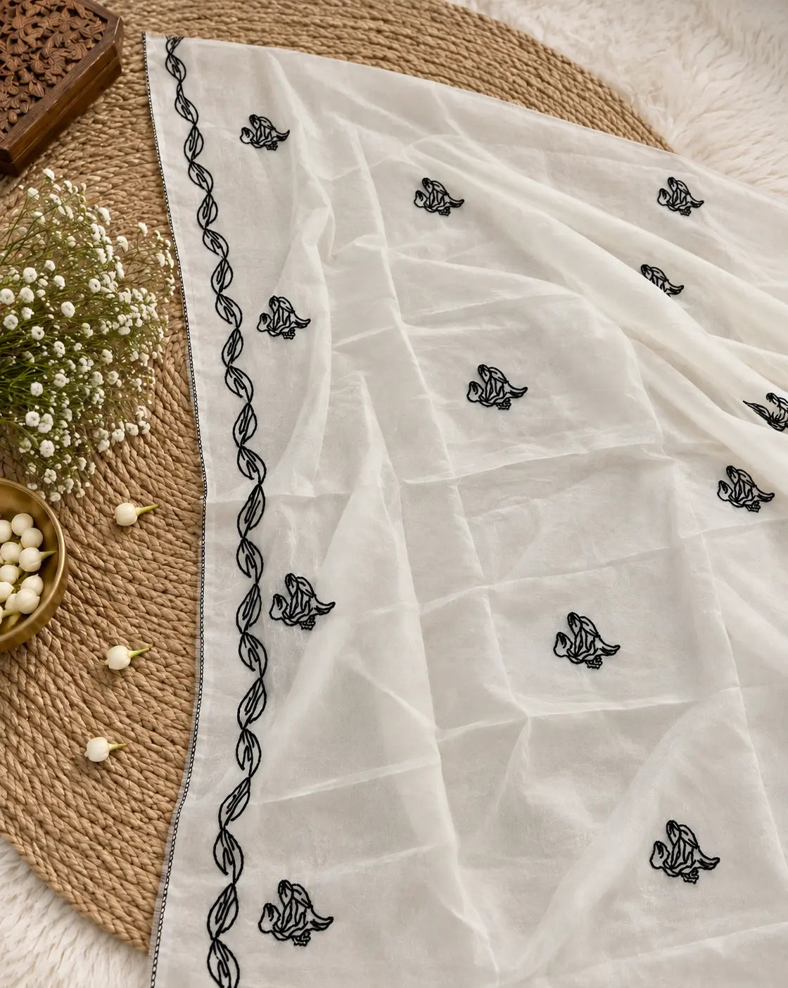 White unstitched suit set featuring black botanical embroidery, floral detailing and elegant embroidered dupatta with leaf border