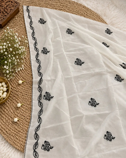 White unstitched suit set featuring black botanical embroidery, floral detailing and elegant embroidered dupatta with leaf border