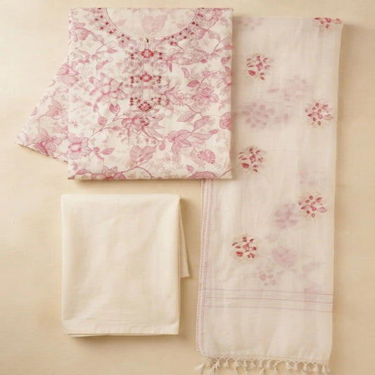 A folded cream-colored cotton fabric set with a pink floral print and a matching cream dupatta featuring pink floral motifs and tassels, laid out on a beige background.