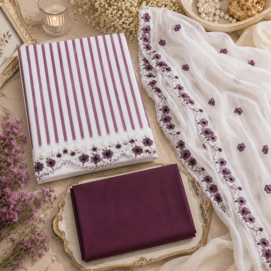 A folded and draped fabric set in purple and white, styled in a decorative flat lay with lace trim, floral embroidery, and a matching solid purple cloth on an ornate tray.